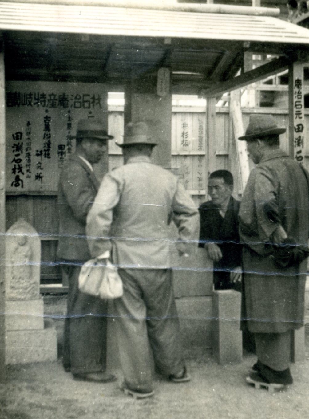 田渕石材の歴史を伝える、石材の看板と人々が写った写真